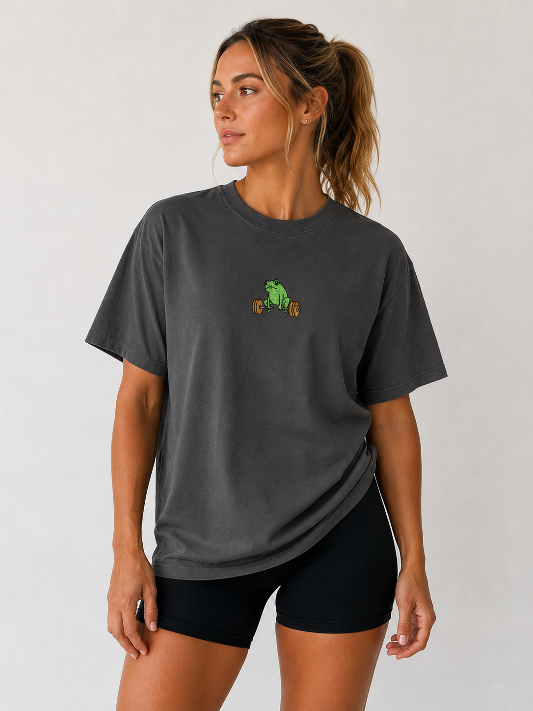 Woman wearing dark gray Global Fitness Co. oversized tee with embroidered frog fitness logo