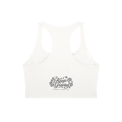 An off-white racerback sports bra with a gray 'Keep Growing Global Fitness Co.' graphic printed on the center front, shown against a plain white background.