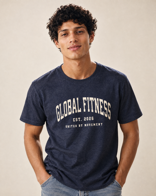 A man wearing a navy blue heathered t-shirt with 'GLOBAL FITNESS EST. 2026 UNITED BY MOVEMENT' printed in white on the front, set against a plain beige background.